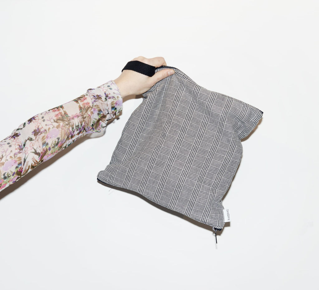 hand of a woman holding up a grey tweed shoofie shoe bag